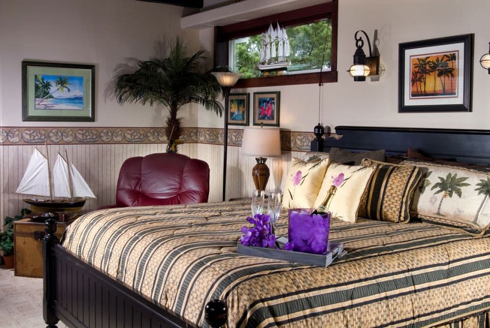Cozy bedroom with a traditional style, featuring striped bedding, framed artwork, and warm lighting.