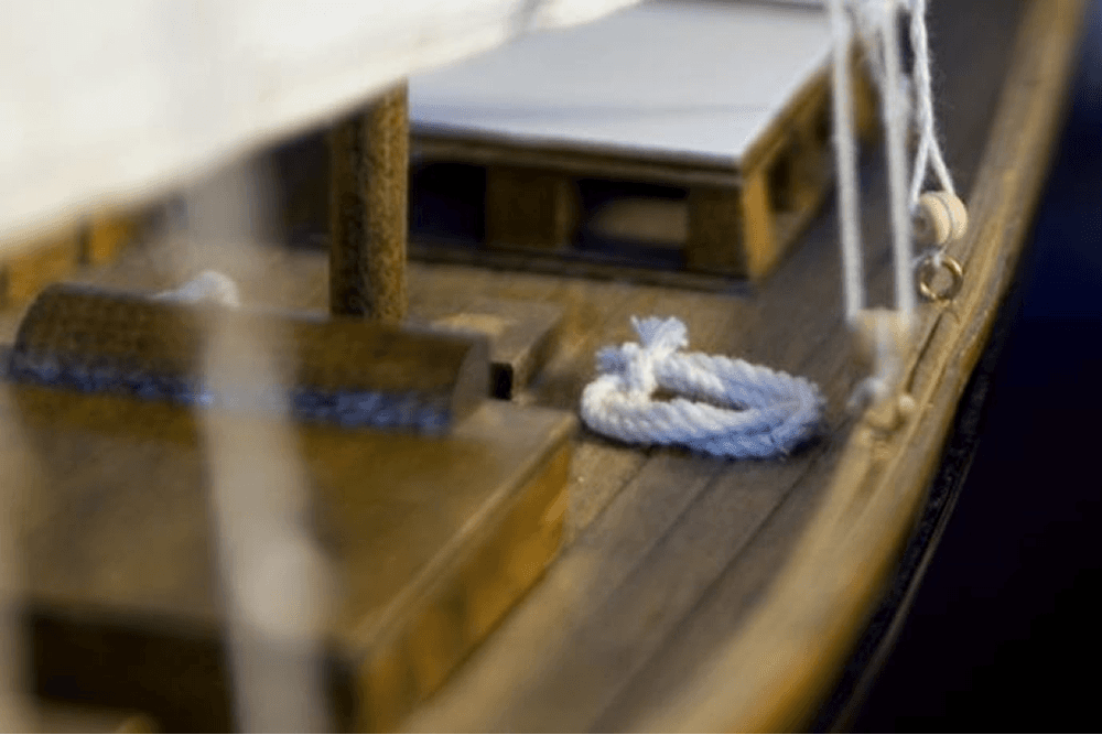 Close-up of a miniature wooden boat with a white rope and wooden details.