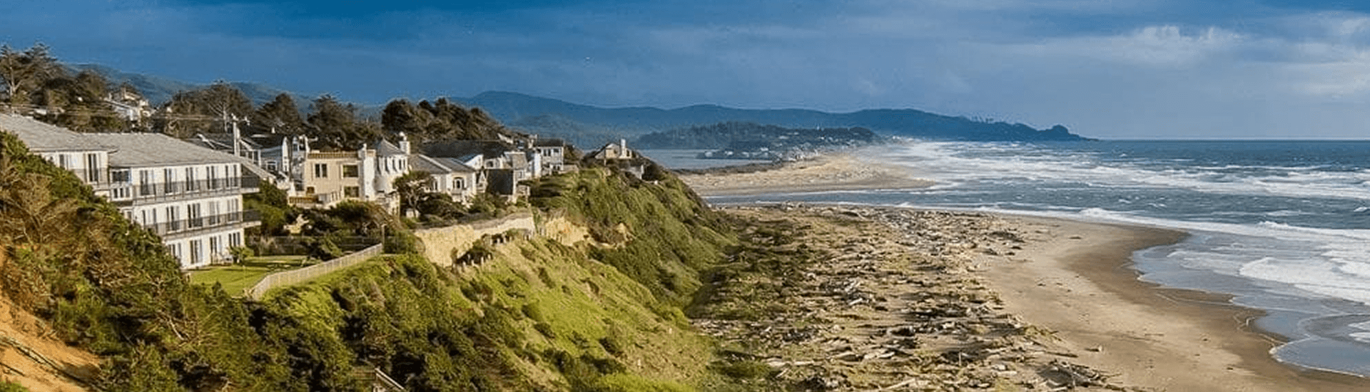 A scenic coastal view featuring cliffs, houses, and a sandy beach.