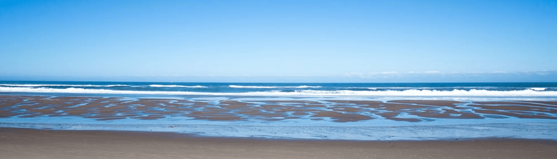 A serene beach scene with gentle waves under a clear blue sky.