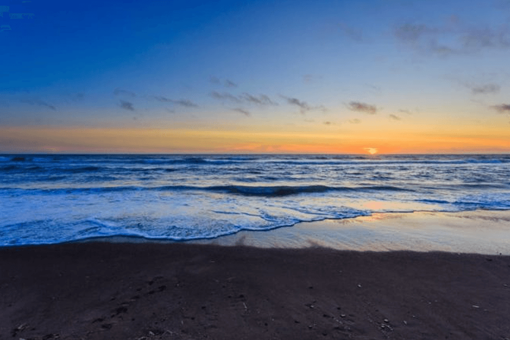 A serene beach at sunset with gentle waves lapping at the shore.