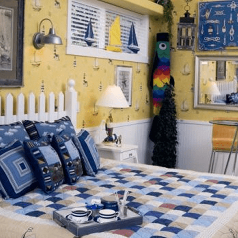 A cozy bedroom featuring a colorful quilt, nautical-themed decor, and a unique rainbow fish figure.