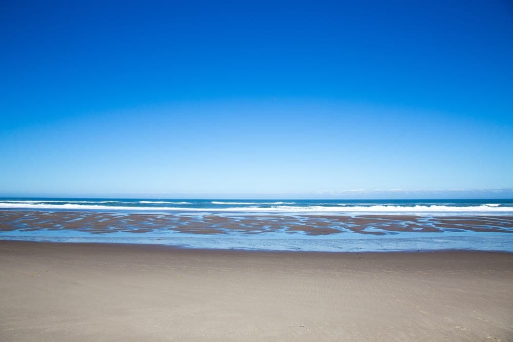 A serene beach with gentle waves under a clear blue sky.