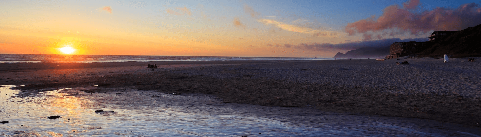 A serene beach at sunset with gentle waves and a colorful sky.
