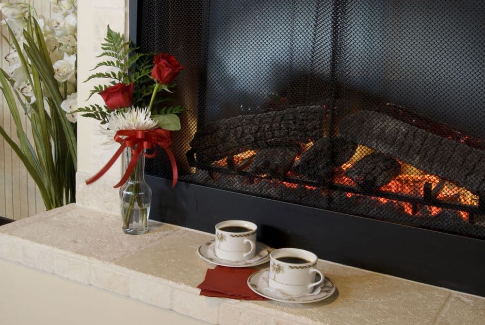 Cozy scene with a fireplace, coffee service, and a decorative floral arrangement.